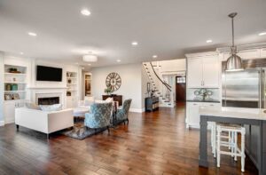 A young couple discusses paperwork at a kitchen table while looking around a sunlit, lived-in living space.