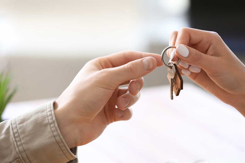 A home inspector examines a kitchen faucet and takes notes on a clipboard.