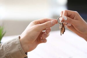 A home inspector examines a kitchen faucet and takes notes on a clipboard.