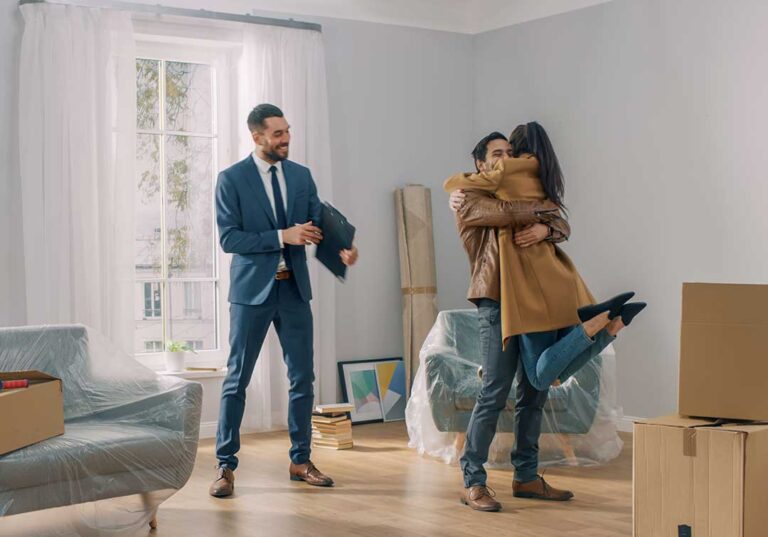 A couple reviews property documents with a real estate agent at a table.